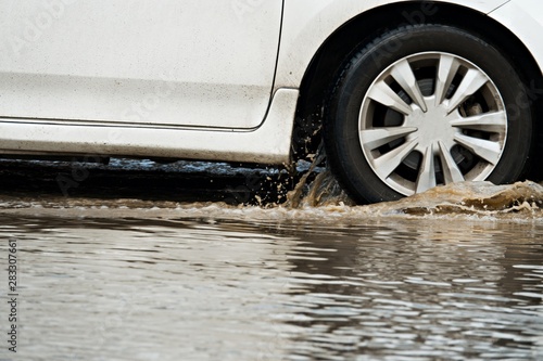 motion car rain big dirty puddle of water spray from the wheels, dangerous for driving.