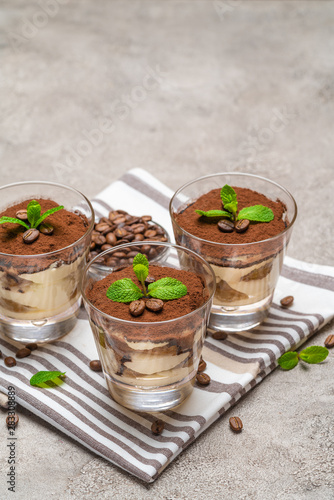 Classic tiramisu dessert in a glass on kitchen towel on concrete background