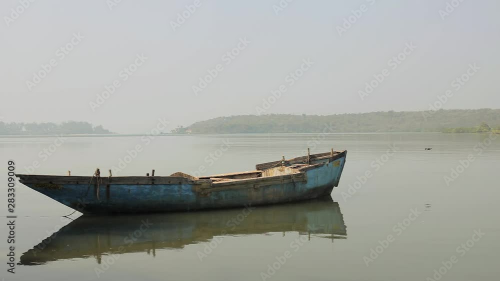 old blue empty shabby boat on the water in the background of the forest old blue empty shabby boat on the water in the background of the forest