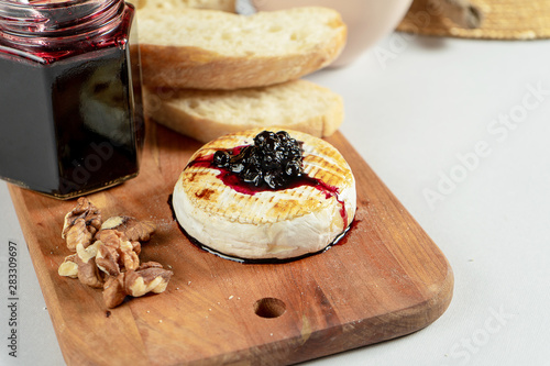 Close up view on grilled camembert with blackberry jam, nuts and chiabatta on grey background. Copy space. Cheese. Tasty food for lunch. Soft focus. Food for wine