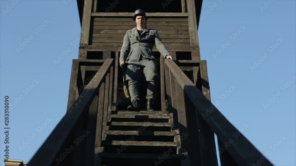 Bottom view of a young German soldier with a rifle going down the stairs of a watchtower. WWII reenactment Bottom view of a young German soldier with a rifle going down the stairs of a watchtower. WWII reenactment