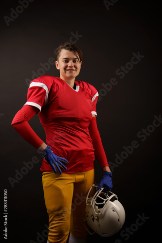 Picture of happy american brunette soccer player with helmet in her hand at empty black background © Sergey