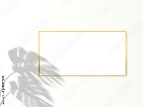 1x2 horizontal Gold frame for photo or picture mockup on white background with shadow of monstera leaves. 3D rendering. photo