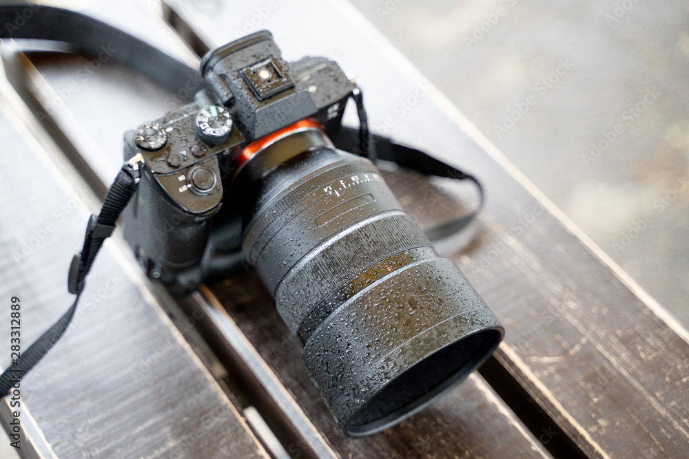 Digital cameras that are wet, rainy, placed on a wooden table Digital cameras that are wet, rainy, placed on a wooden table