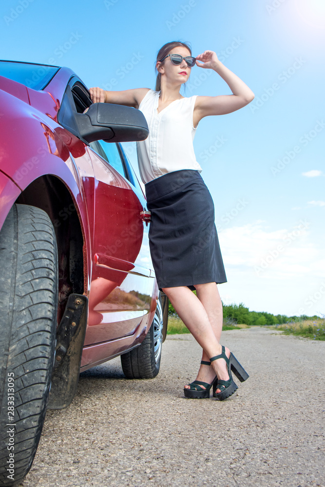 Fototapeta premium young business woman with car. Sexy rich fashion girl posing near red car.