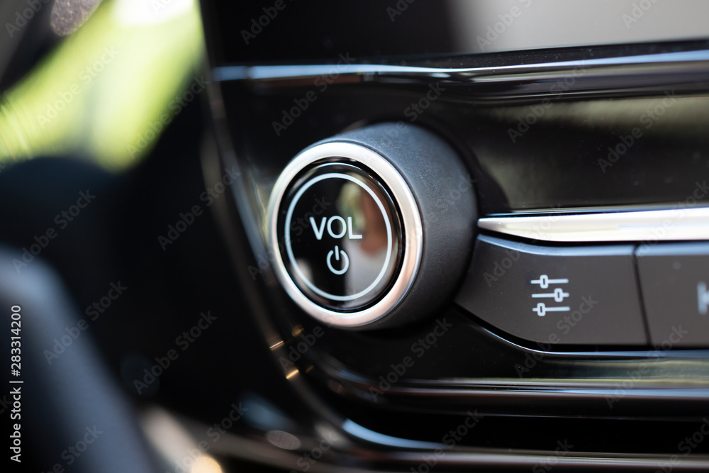 Volume button on a modern car. Black knob with chrome trim.