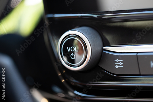 Volume button on a modern car. Black knob with chrome trim.