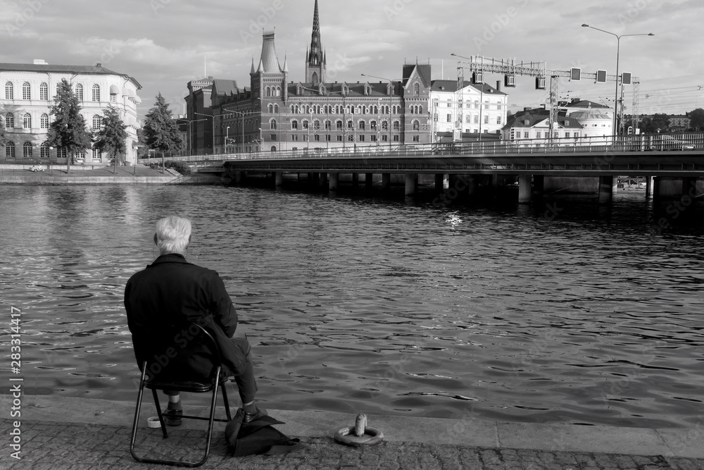 alter Mann sitzt an Kanal