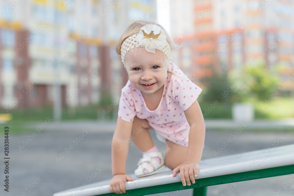 a little girl playing on the Playground in the yard near the house . Child baby climb up on toy climbed on a ladder or swing a little girl playing on the Playground in the yard near the house . Child baby climb up on toy climbed on a ladder or swing