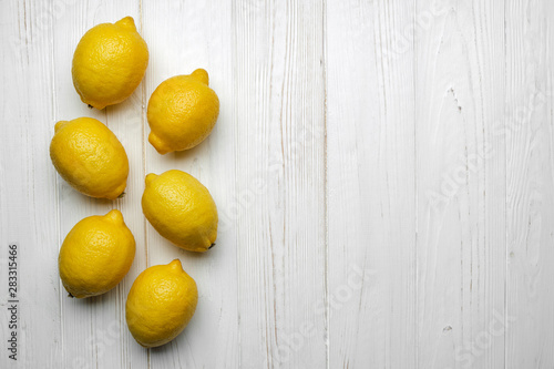fresh whole yellow lemons on white wood background with space for text. top view