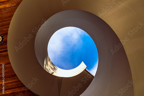 Fototapeta Naklejka Na Ścianę i Meble -  A spiral staircase leading to a blue sky at a public access garden in Docklands, Melbourne, Australia