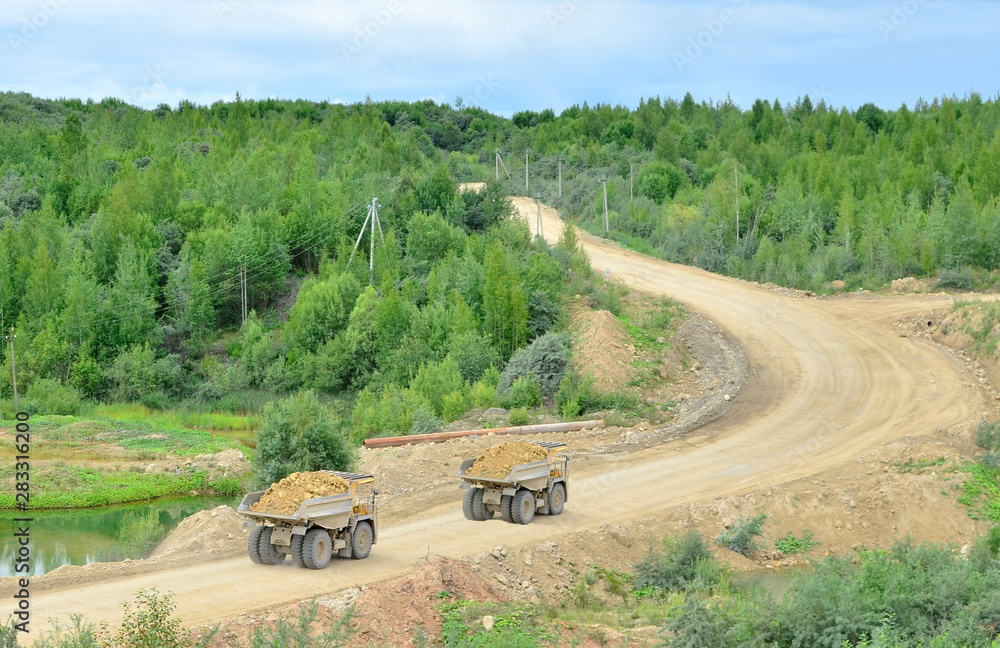 Big yellow dump truck working in the limestone open-pit. Loading and transportation of minerals in the dolomite mining quarry. Belarus, Vitebsk, in the largest i dolomite deposit, quarry 