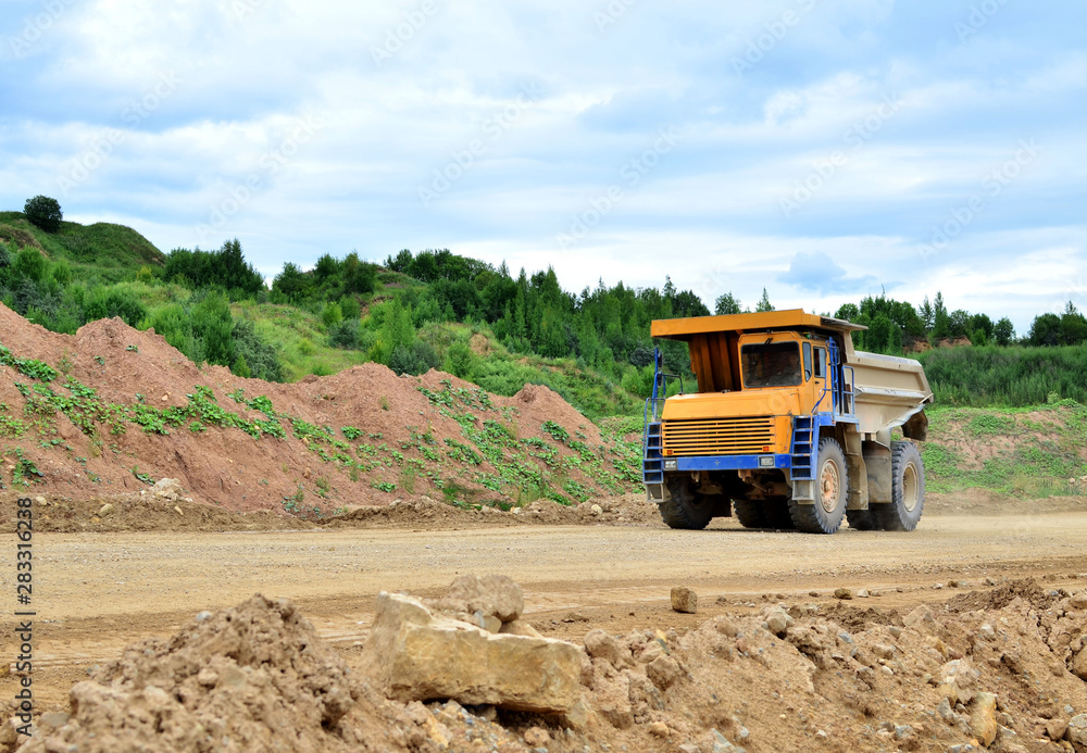 Big yellow dump truck working in the limestone open-pit. Loading and transportation of minerals in the dolomite mining quarry. Belarus, Vitebsk, in the largest i dolomite deposit, quarry 