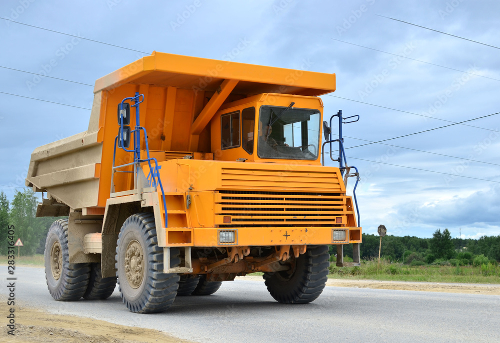 Big yellow dump truck working in the limestone open-pit. Loading and transportation of minerals in the dolomite mining quarry. Belarus, Vitebsk, in the largest i dolomite deposit, quarry 