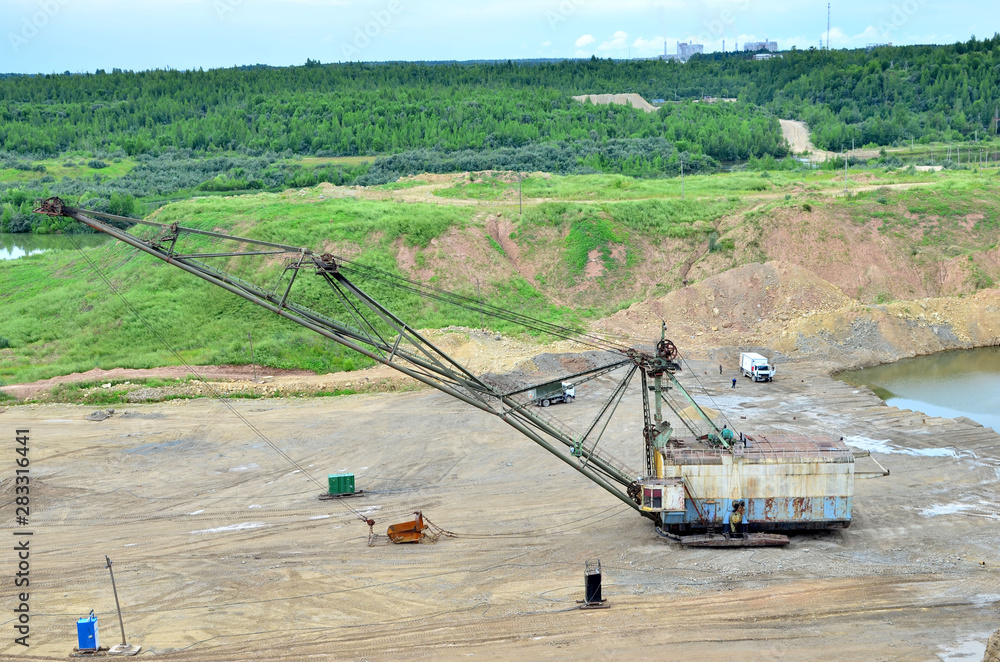 Fototapeta premium Biggest excavator dragline with a large bucket for the quarry overburden stripping. Belarus, Vitebsk, largest dolomite deposit in a open pit 
