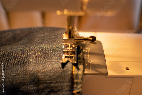 Jeans hem in the sewing machine ready to get cut
