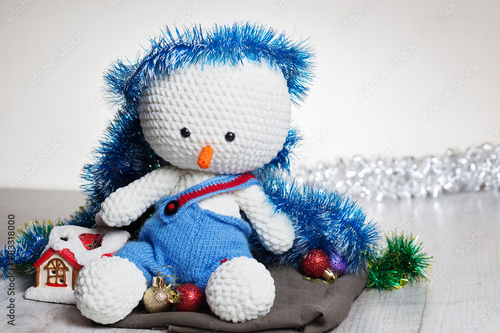 Сrocheted soft toy snowman in blue pants on table,close-up,space for text.Celebrating christmas - winter concept Сrocheted soft toy snowman in blue pants on table,close-up,space for text.Celebrating christmas - winter concept