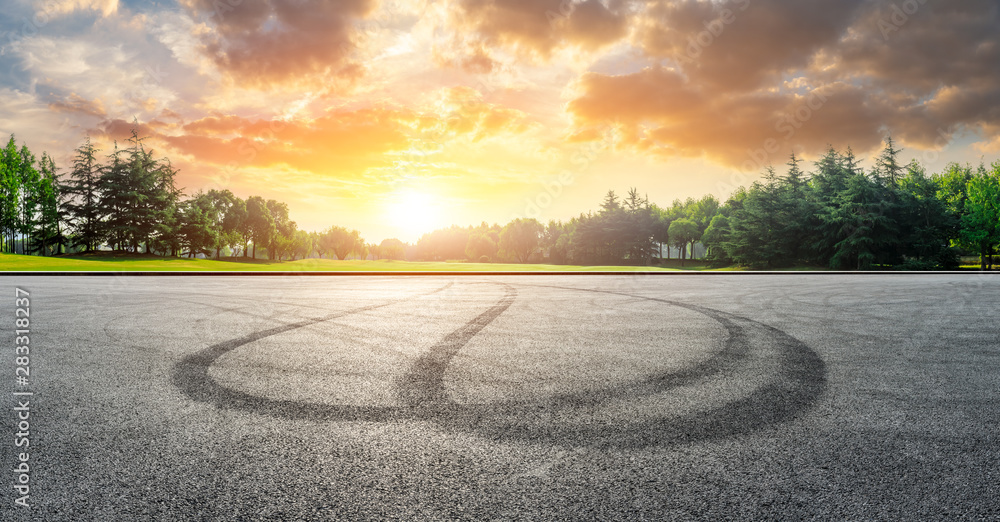 Fototapeta premium Asphalt race track and green woods nature landscape at sunset