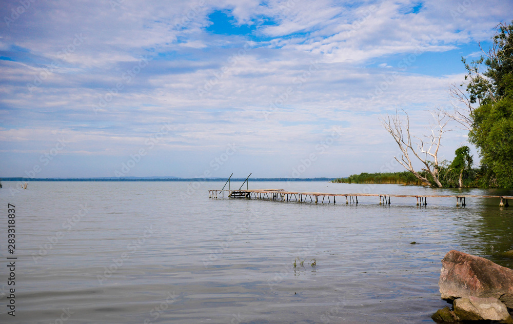 Obraz premium Empty wood deck at Balaton lakeshore in the morning hours with cloudy sky.