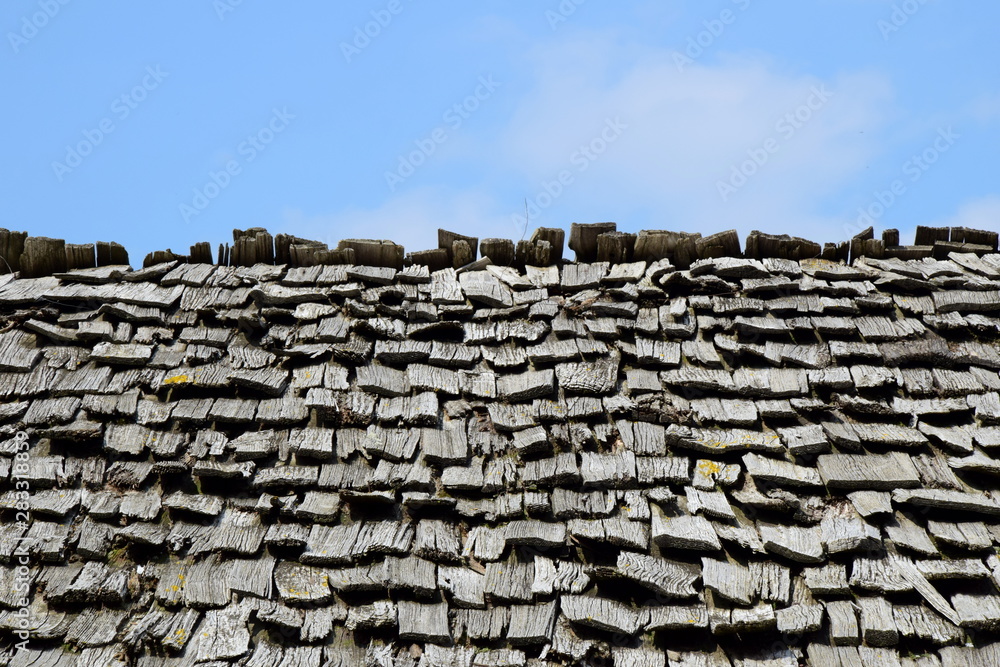 Altes graues verwittertes Schindeldach mit blauen Himmel als Hintergrund Altes graues verwittertes Schindeldach mit blauen Himmel als Hintergrund