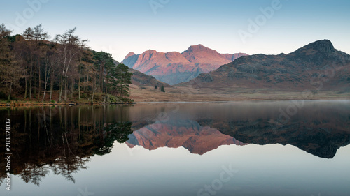 Beautiful Autumn Fall colorful sunrise over Blea Tarn in the Lake District with High Raise and The Langdales in the distance