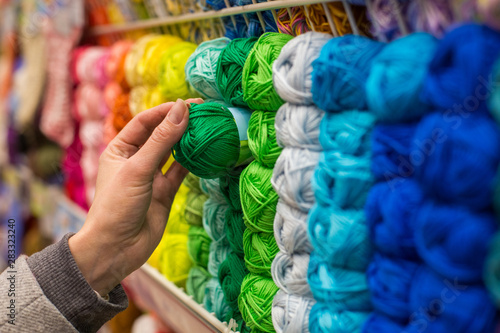 Close Up of yarn balls. Girl hand choosing Yarn in Knitting Shop. knitting shop center. A lot of color yarn for knitting. Selection of colorful yarn wool on shopfront © chibelek