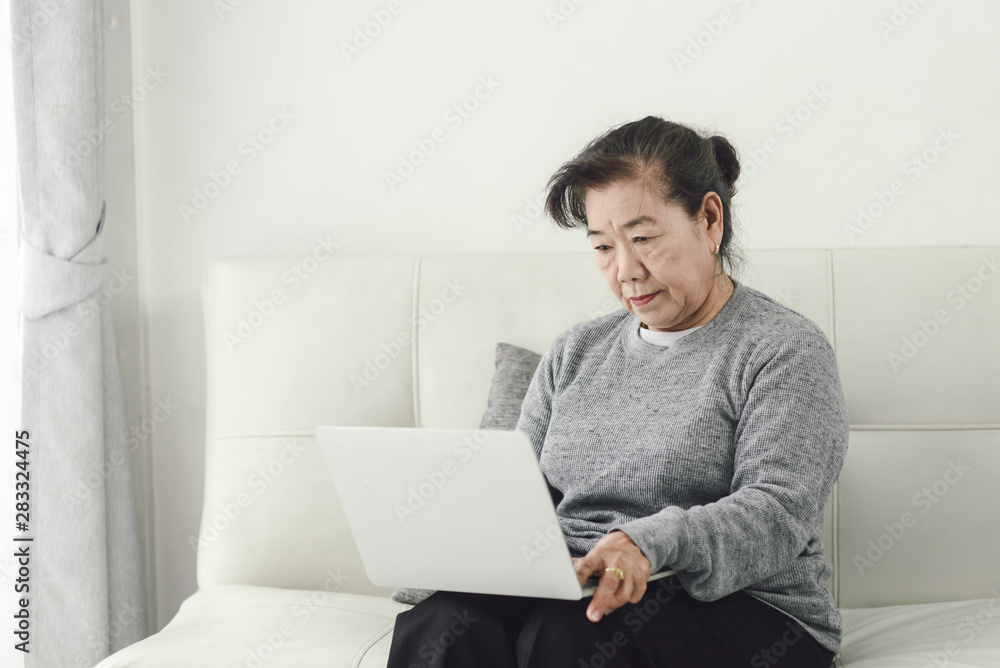 Asian senior woman using laptop at home, lifestyle concept.
