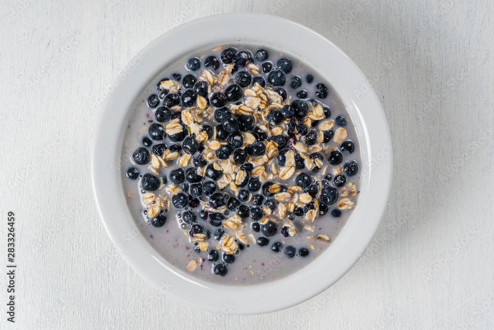 Oatmeal with fresh blueberry, almond milk and honey for breakfast in plate on wooden background. Rustic style. Top view. Oatmeal with fresh blueberry, almond milk and honey for breakfast in plate on wooden background. Rustic style. Top view.