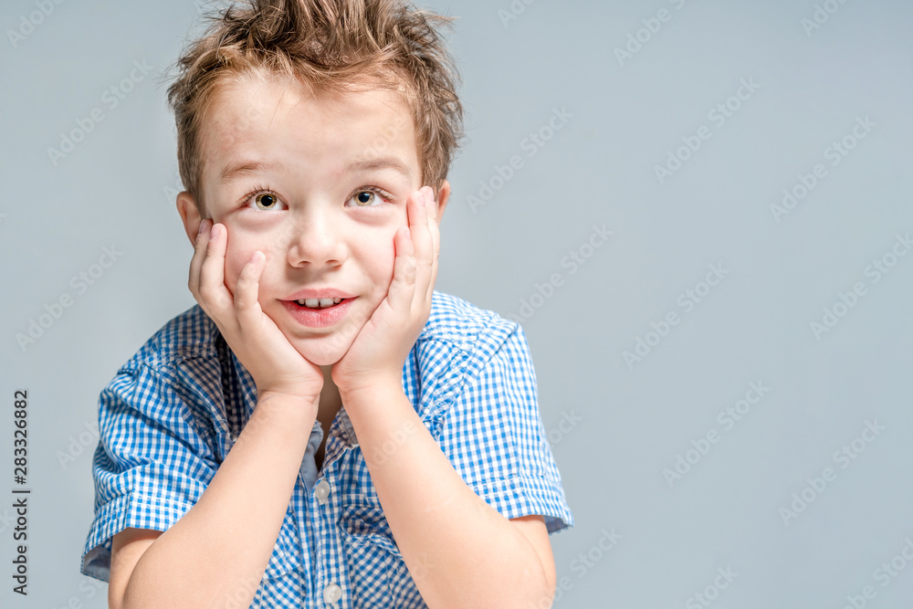 Smiling boy sitting on a gray background in the studio. Isolated. Smiling boy sitting on a gray background in the studio. Isolated.
