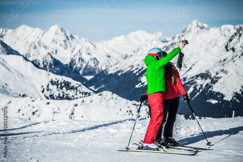 Skifahrer im Winterurlaub die mit ihrem Smartphone ein gemeinsames Selfie als Erinnerung machen