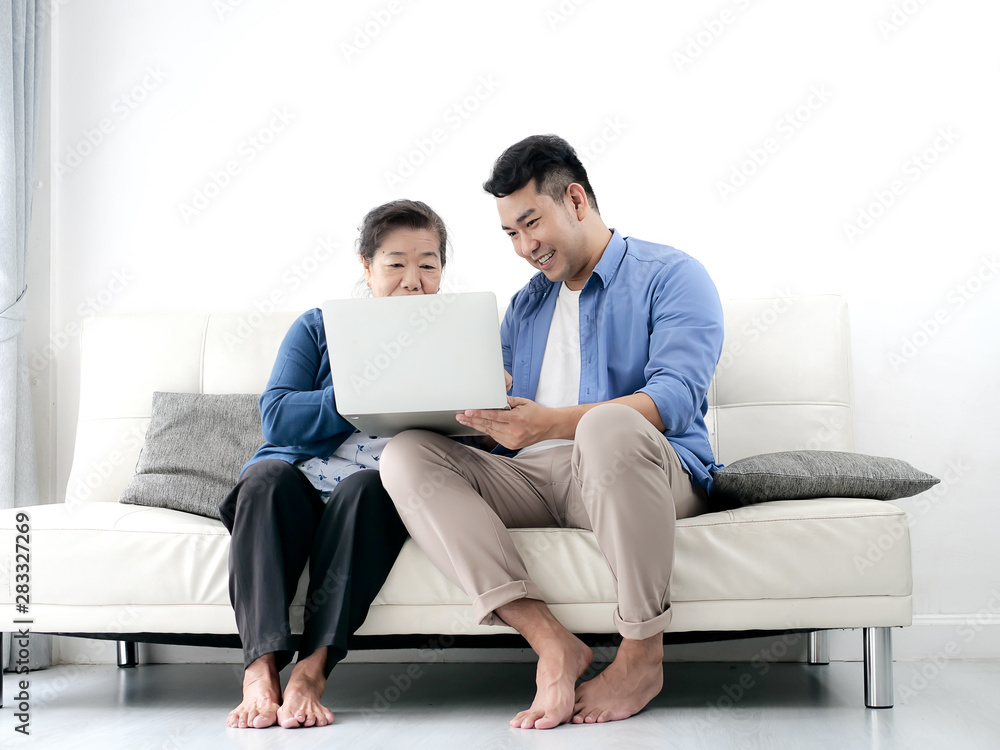 Asian man teaching his mother using laptop at home, technology concept. Asian man teaching his mother using laptop at home, technology concept.