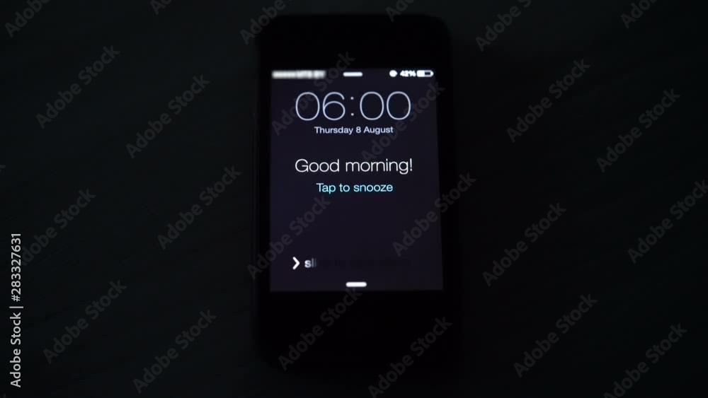 Good morning alarm clock on the phone in the dark room, closeup Stock