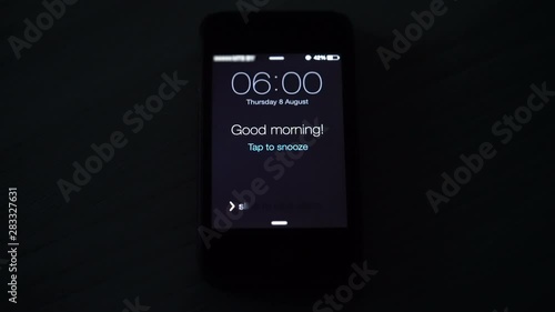 Good morning alarm clock on the phone in the dark room, close-up