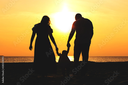 silhouette of a family with a child by the sea at sunset