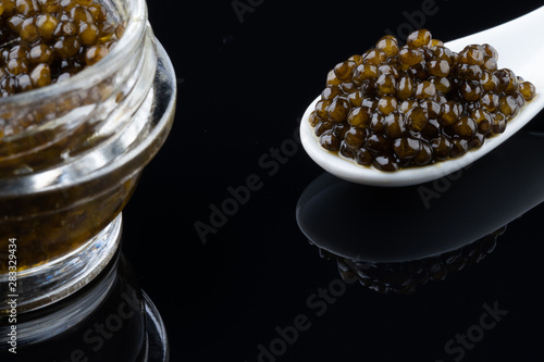 Fotografie Black sturgeon caviar in ceramic spoon. macro