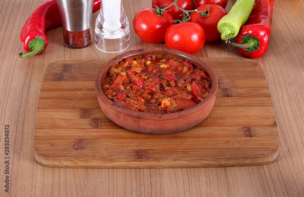Serving fresh meat in earthenware dish with red and green pepper Serving fresh meat in earthenware dish with red and green pepper