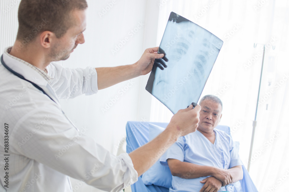 Obraz premium Doctor look at X-ray film and basic diagnosis tuberculosis of old patient