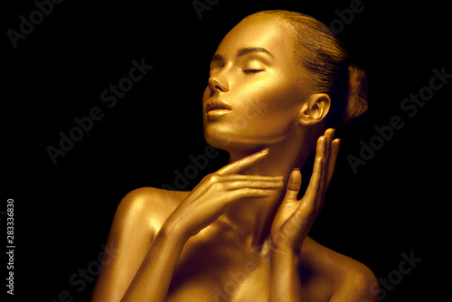 Model girl with shiny golden professional makeup over black. Beauty sexy woman with golden skin. Fashion art portrait closeup. Gold jewellery