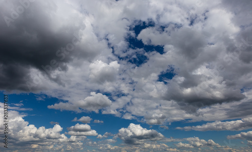 Cumulus fluffy clouds in the blue sky. Harbingers of rain. Sky pattern. 