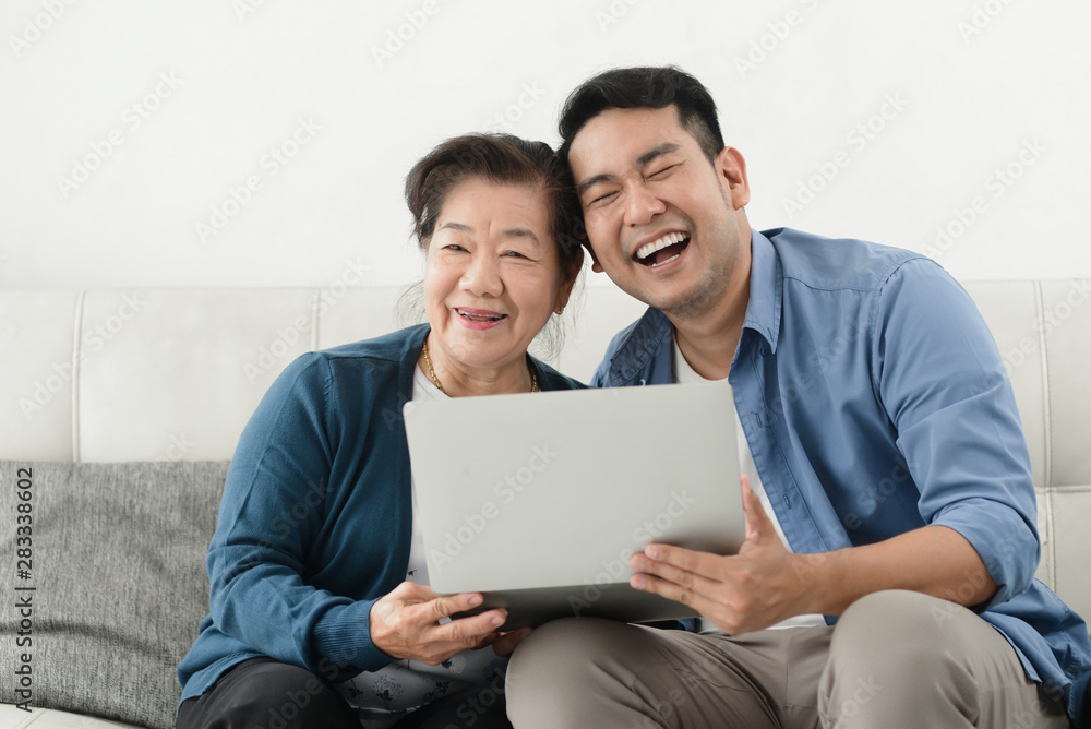 Asian man teaching his mother using laptop at home, technology concept. Asian man teaching his mother using laptop at home, technology concept.