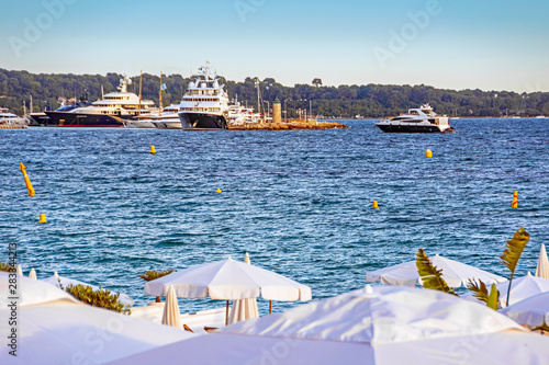 Sea bay with yachts boats and beach umbrella in Cannes