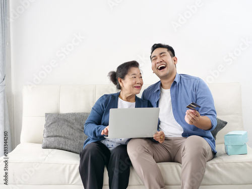 Asian man teaching his mother for shopping online, modern lifestyle concept. © nuiiko
