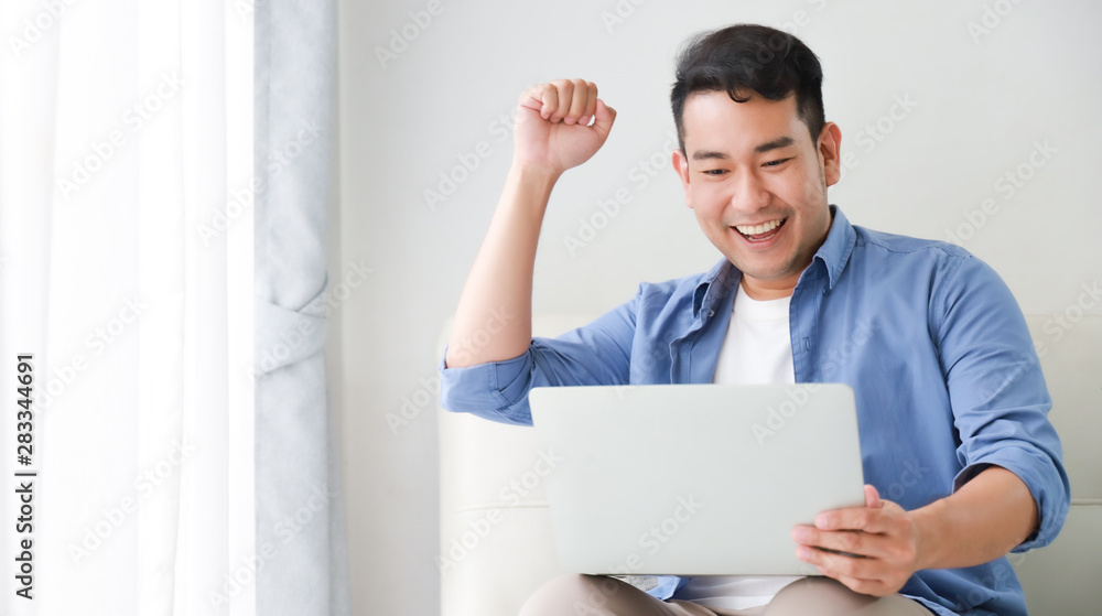 Asian handsome man working with laptop computer in living room happy and smile face Asian handsome man working with laptop computer in living room happy and smile face