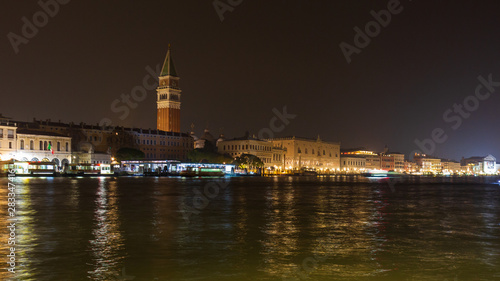 Bell tower and historical buildings at night at Piazza San Marco from the Basilica di Santa Maria della Salute in Venice, Italy.