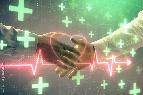 Multi exposure of heart hologram on abstract background with two men handshake. Concept of medical education