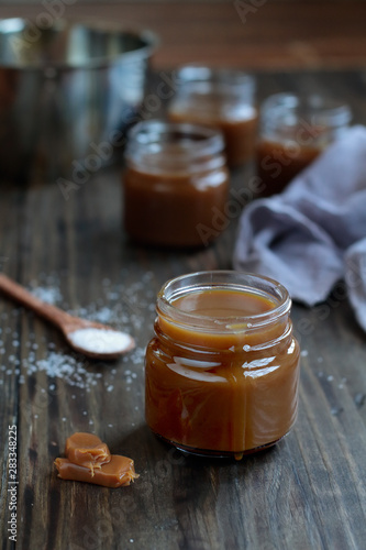 Little jars of salted caramel sauce over a rustic table. Selective focus with blurred background.