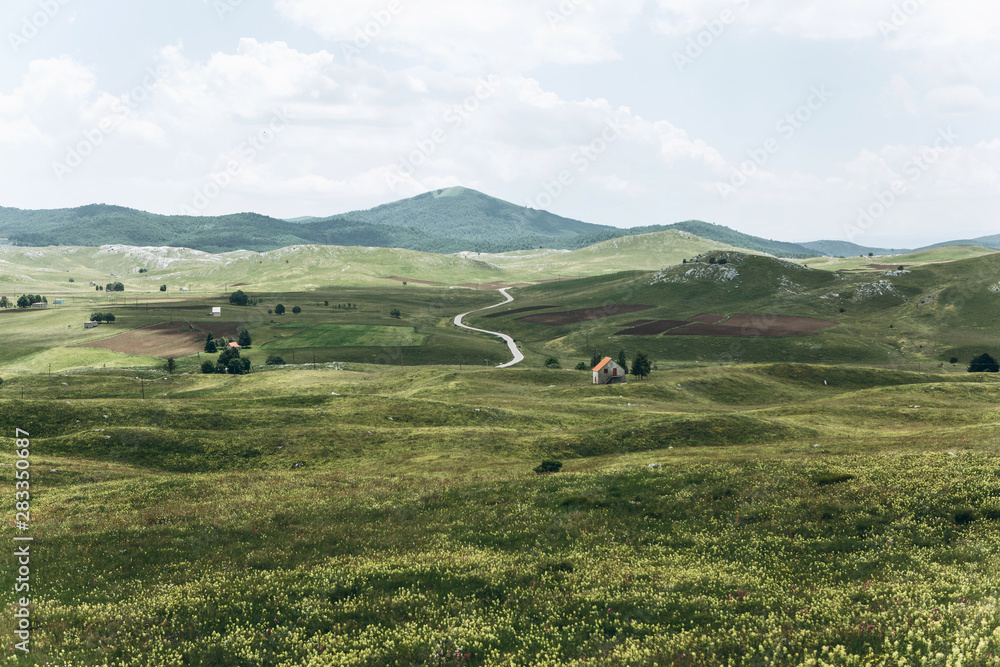 Obraz premium Beautiful view of the natural landscape in Montenegro with a field and authentic houses with a mountain in the background.