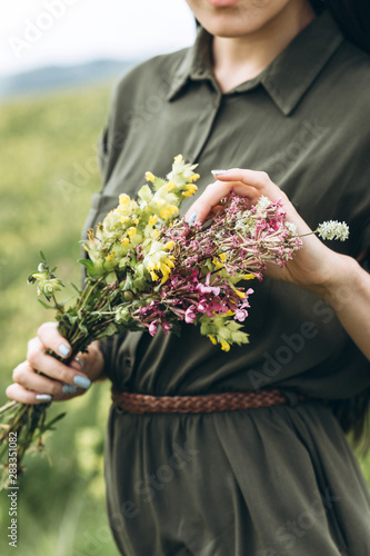 Close-up of a girl holding wildflowers in her hands.