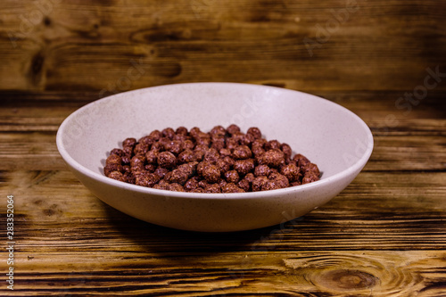 Ceramic plate with chocolate cereal balls on wooden table