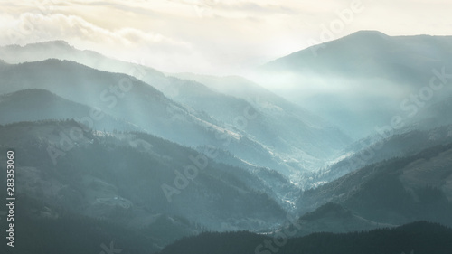 Mountain landscape. View of Carpathian mountain range with visible silhouettes through the colorful fog.
